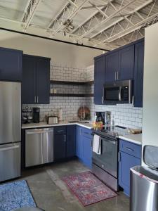 uma cozinha com armários azuis e electrodomésticos de aço inoxidável em Silo View - heart of downtown em Waco
