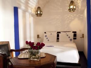 Un dormitorio con una cama y una mesa con flores. en Riad ka, en Marrakech