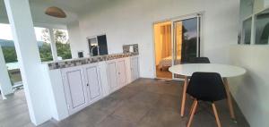 a kitchen with a table and a table and chairs at El-Sangha Studio 2mina pieds de la plage de baie du cap in Ruisseau Créole