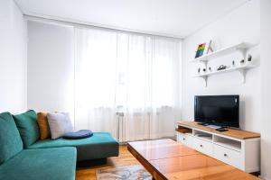een woonkamer met een groene bank en een tv bij Contemporary Comfort: 1BD Flat in Lozenetz, Sofia in Sofia