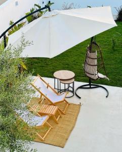 uma mesa e cadeiras sob um guarda-sol branco em Dar Oliva Maison de luxe em Houmt Souk