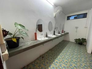 uma casa de banho com uma fila de lavatórios e espelhos em ANOU HOSTEL em Pakse