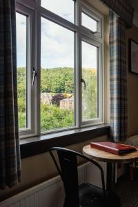 una finestra in una stanza con un tavolo e un libro di Traquair Arms Hotel a Innerleithen