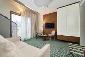 Cette chambre d'hôtel dispose d'un canapé blanc et d'une télévision. dans l'établissement GWARNA Aparthotel City Center Wrocław by Renters, à Wrocław