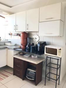 a kitchen with white cabinets and a counter with a microwave at Aconchegante, ótima localização e vista para o mar in Recife