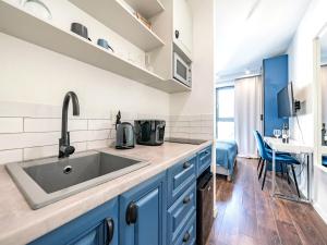 - une cuisine avec des placards bleus et un évier dans l'établissement Hello Apartments Classy Industrial Browar Gdansk, à Gdańsk