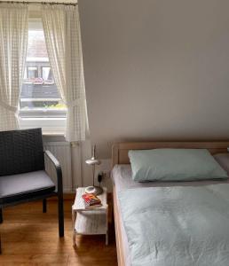1 dormitorio con 1 cama, 1 silla y 1 ventana en Aalhues-Ferienwohnung-ueber-2-Etagen-fuer-4-Erwachsene-und-1-Kind en Westerland