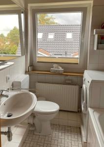 baño con lavabo y aseo y ventana en Aalhues-Ferienwohnung-ueber-2-Etagen-fuer-4-Erwachsene-und-1-Kind en Westerland