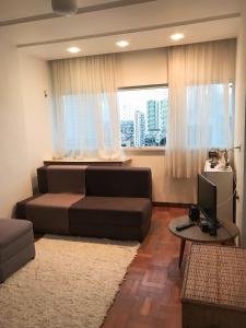 um quarto com uma cama, uma secretária e uma televisão em Aconchegante, ótima localização e vista para o mar no Recife