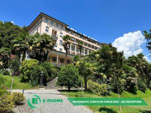 a large building with palm trees in front of it at E-Rooms Minusio in Locarno