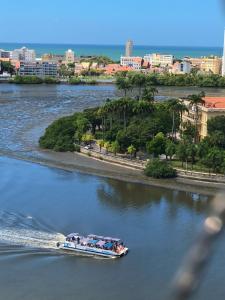 a boat on a river with a city in the background at Aconchegante, ótima localização e vista para o mar in Recife