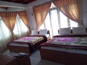 two beds sitting in a room with windows at Oviya Guest in Nuwara Eliya