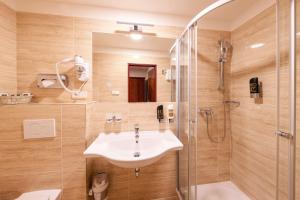 La salle de bains est pourvue d'un lavabo et d'une douche. dans l'établissement Hotel Meteor Plaza Prague, à Prague