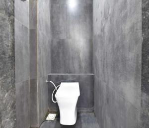 a bathroom with a white toilet in a wall at Hotel Infini Palace City Center in Surat