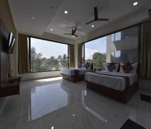 a large bedroom with two beds and a large window at Hotel Infini Palace City Center in Surat