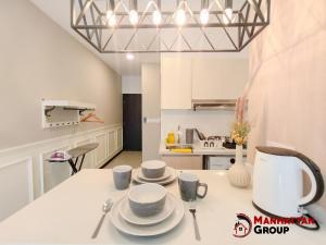 eine Küche mit einem Tisch mit Tassen und Untertassen darauf in der Unterkunft Neu Suites By Manhattan Group in Kuala Lumpur
