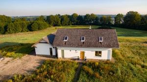 a small white house with a roof on a field at Wilczy Zew Private Spa & Nature in Borne