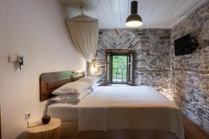 een slaapkamer met een bed en een stenen muur bij Mountain's Secret in Mouresi