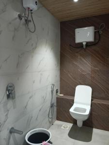 ムンバイにあるHotel Palms Residency, Chembur Mumbaiのバスルーム(白いトイレ、シャワー付)