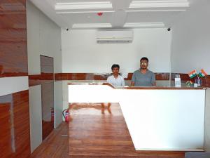 ムンバイにあるHotel Palms Residency, Chembur Mumbaiの二人の男が部屋のカウンターに立っている