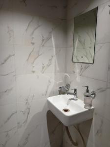 a white bathroom with a sink and a mirror at Hotel Palms Residency, Chembur Mumbai in Mumbai