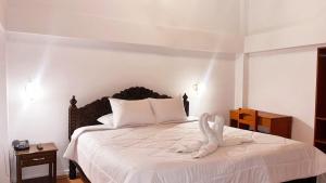 1 dormitorio con 1 cama con colcha blanca en SAN BLAS PLAZA INn, en Cusco