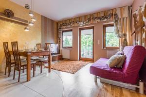 sala de estar con mesa y sofá púrpura en Apartamenty Bystra Woda Zakopane, en Zakopane