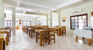 a dining room with wooden tables and chairs at Pousada Sol e Praia in Torres