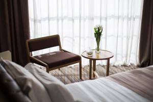Un dormitorio con una silla y una mesa con un jarrón de flores en Jump INN Hotel Belgrade, en Belgrado