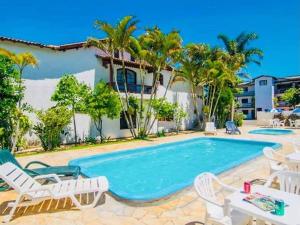托雷斯的住宿－Pousada Sol e Praia，一座带白色椅子的游泳池和一座建筑