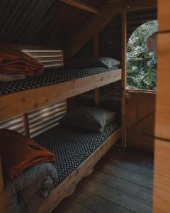 two bunk beds in a wooden cabin with a window at Architectural Danish Cabin surrounded by nature in Treknow