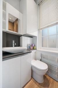 a white bathroom with a toilet and a sink at Superb One Bedroom Apartment in Soho in London