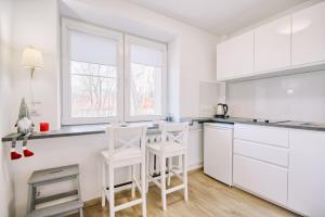 een witte keuken met witte kasten en witte krukken bij DaGys apartments in Druskininkai