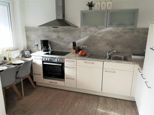 a kitchen with white cabinets and a sink and a stove at Butze Ferienapartment in Büsum