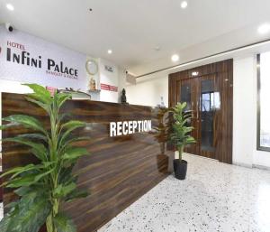 a lobby with a reception desk and two plants at Hotel Infini Palace City Center in Surat