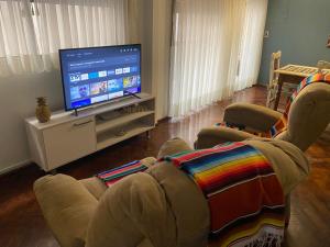 a living room with two chairs and a flat screen tv at Alquiler cálido departamento en el corazon mendocino in Mendoza