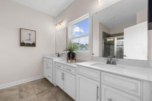 a white bathroom with two sinks and a window at Luxurious 3 Story Townhome! The Dye at Barefoot Resort 402- Sleeps 12! in North Myrtle Beach