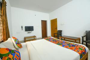 1 dormitorio con 1 cama y TV en la pared en FabHotel Joy's Residency en Coimbatore