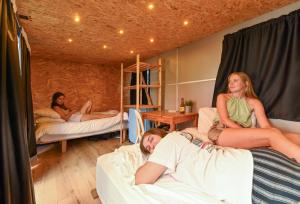 three girls laying on beds in a room at Caravan Hostel Tel Aviv By Roger Age 18-45 in Tel Aviv