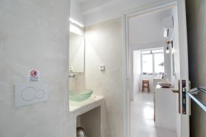 Un baño blanco con lavabo y espejo. en Helmos Cozy Studio, en Naxos Chora