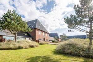 a brick building with trees in the yard at Steger-Hüs Wohnung 13 in Rantum