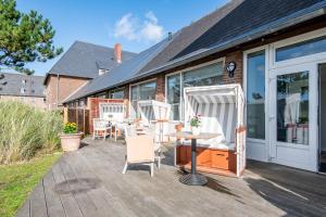 a patio with white chairs and a table on it at Steger-Hüs Lounge in Rantum
