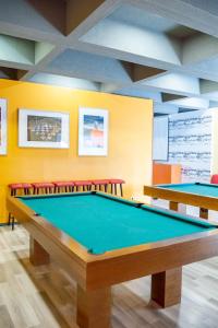 a billiard room with two tables and red chairs at Mobility Friends Hostel in Barcelos