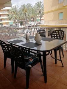un tavolo e sedie su un balcone con palme di Sencillo apartamento en primera línea de playa a Tavernes de Valldigna