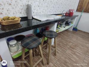 Suíte GUARAMIRANGA no Sítio في غواراميرانغا: مطبخ مع كرسيين تحت كونتر مطبخ