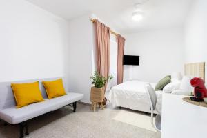 ein weißes Wohnzimmer mit gelben Kissen und einer Couch in der Unterkunft EDEN RENTALS 106 Surfy Stylish Bed&Coffee Room in Granadilla de Abona