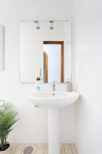 Baño blanco con lavabo y espejo en EDEN RENTALS 106 Surfy Stylish Bed&Coffee Room en Granadilla de Abona