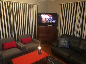 ein Wohnzimmer mit zwei Sofas und einem Fernseher in der Unterkunft Emma's Beach Cottage in Groot Brak Rivier