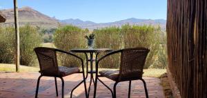 una mesa y 2 sillas en un patio con vistas en Mashai Rest Rondavel, en Underberg