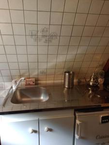 eine Küche mit einem Waschbecken und einer gefliesten Wand in der Unterkunft Micro maison ISBA Sedan in Givonne